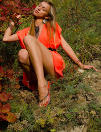 Sofy B: Verba by Antonio Clemens - A smiling and confident Sofy frolics among the grass and plants in her bright orange dress like a carefree forest n